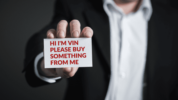 A man in suit holding out a name card.