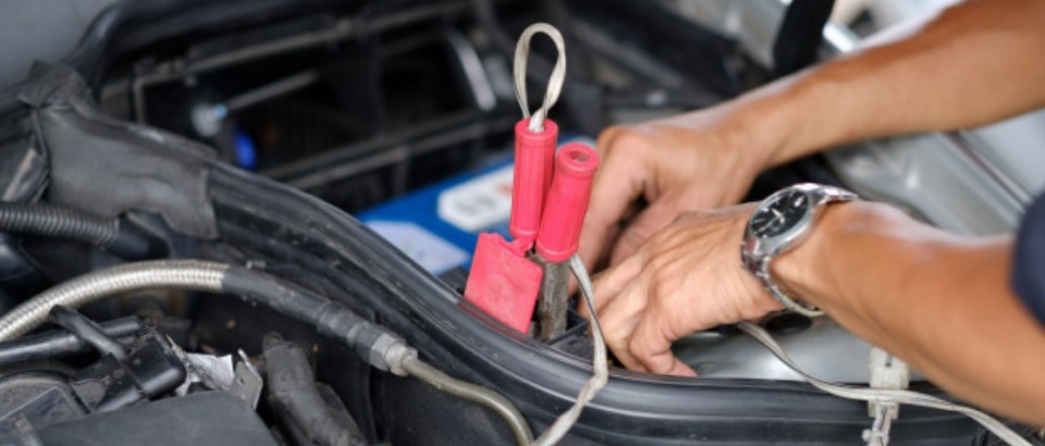 hands working on changing car battery