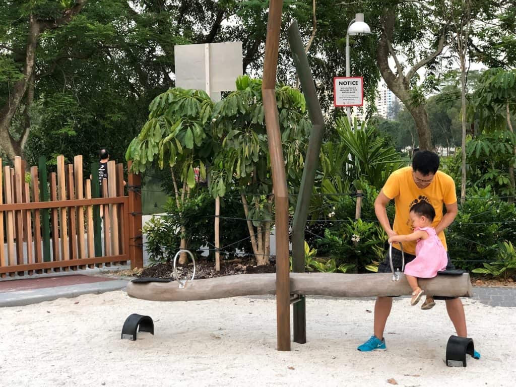 man holding child sitting on seesaw